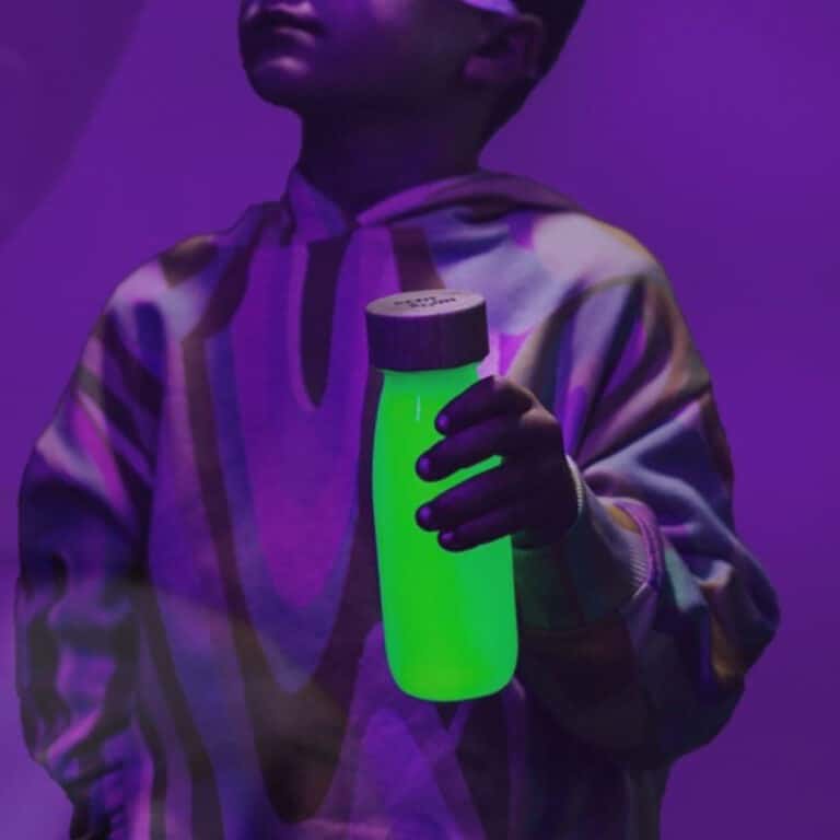 une bouteille sensorielle jaune fluo, vue dans le noir