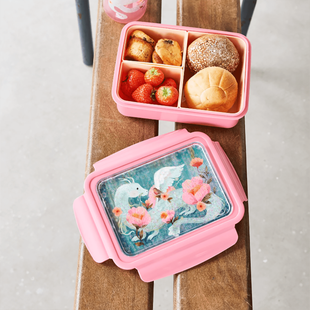 une boîte à repas lapin avec un couvercle à paillettes. Il y a trois compartiments amovibles. Vue de face et utilisée sur un fond de décoration