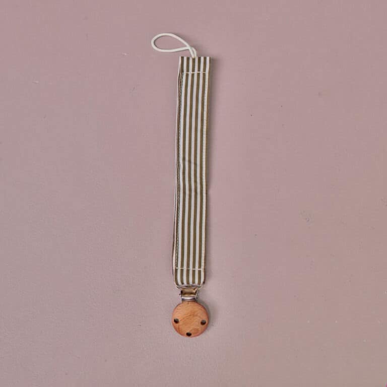 attache tétine à rayures kaki gabrielle paris sur fond rose