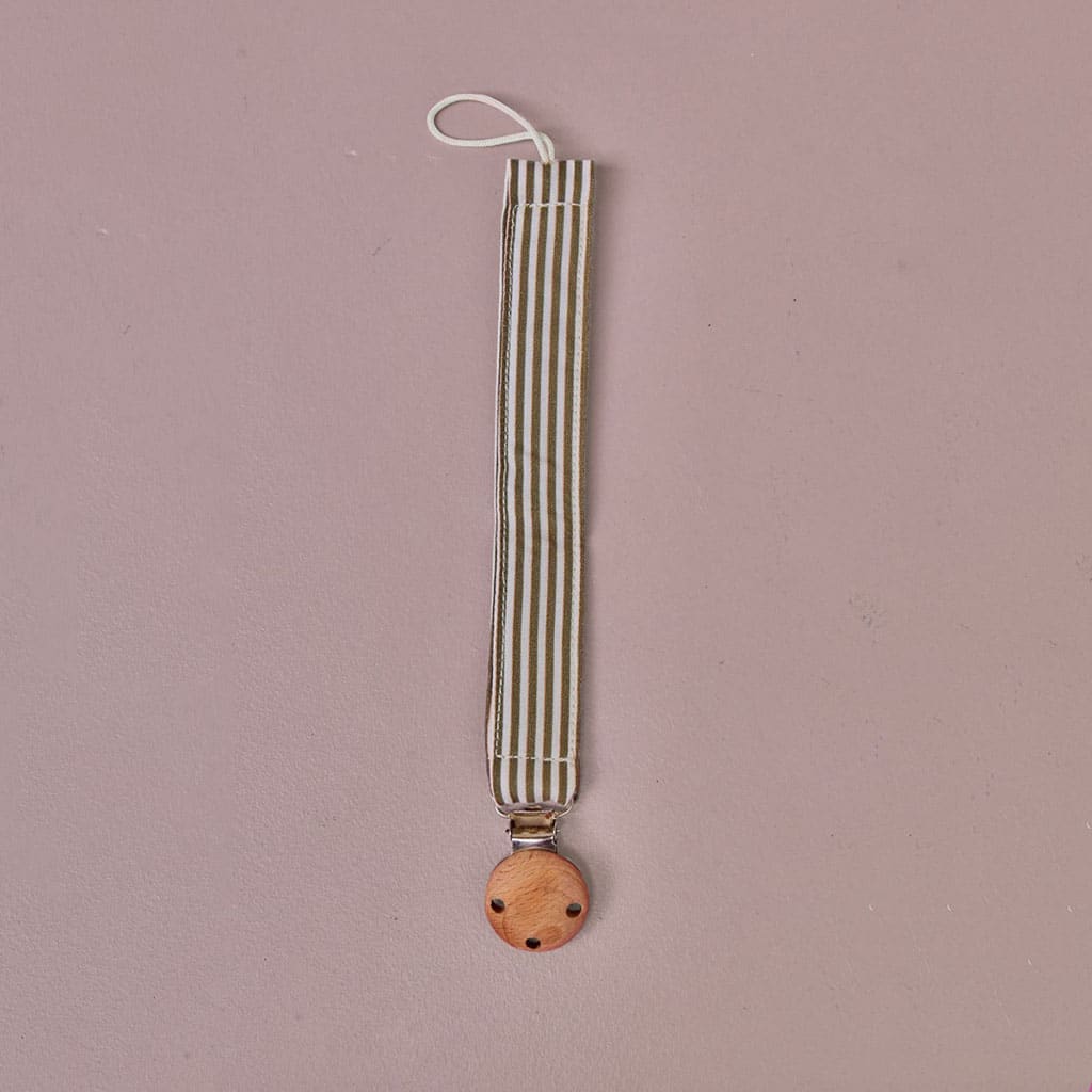 attache tétine à rayures kaki gabrielle paris sur fond rose