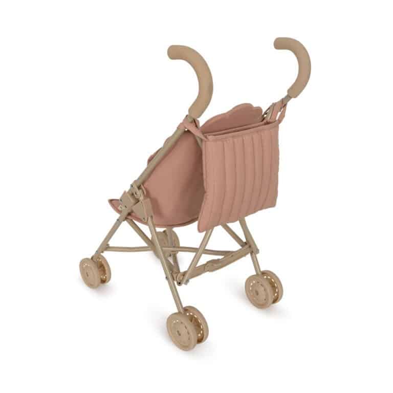 une poussette rose avec une petite cerise Konges Slojd, vue de dos sur fond blanc