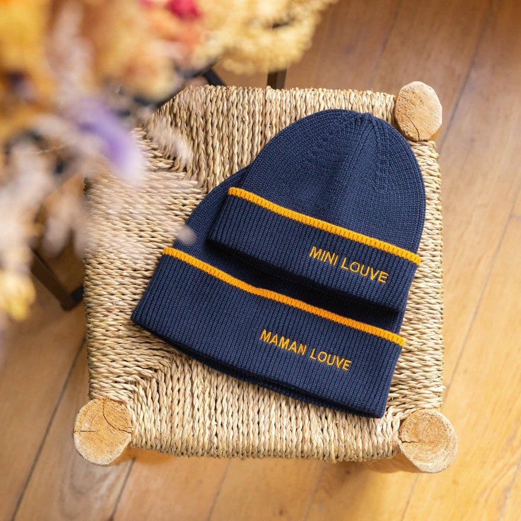 deux bonnets "mini louve" et "Maman louve" bleu marine chamaye, vues de face sur un fond décoré