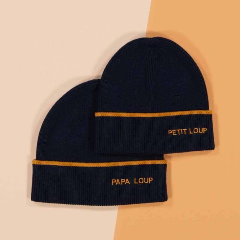 deux bonnets "Petit loup" et "Papa Loup" bleu marine chamaye, vues de face sur un fond décoré