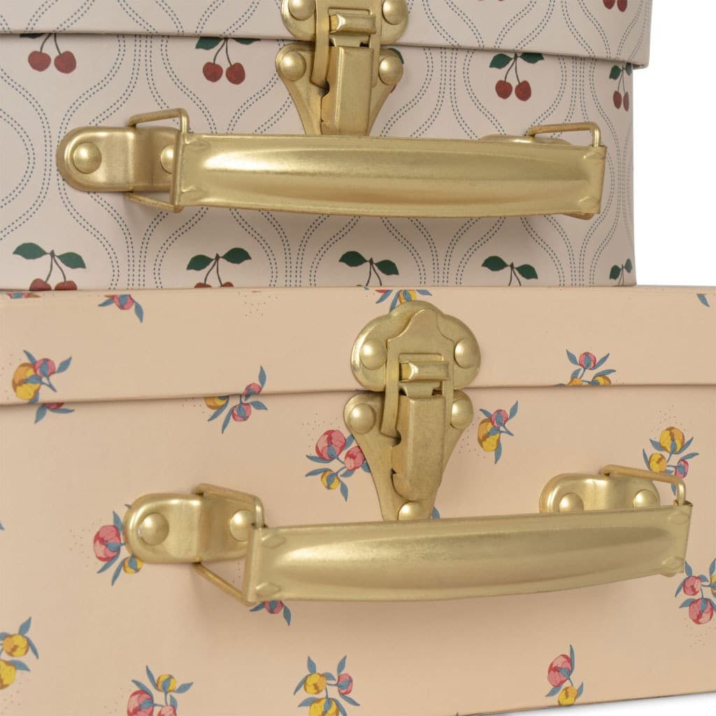 une petite valisette cerises et une grande valisette fleurs Konges Slojd, zoom sur les motifs et les attaches sur fond blanc