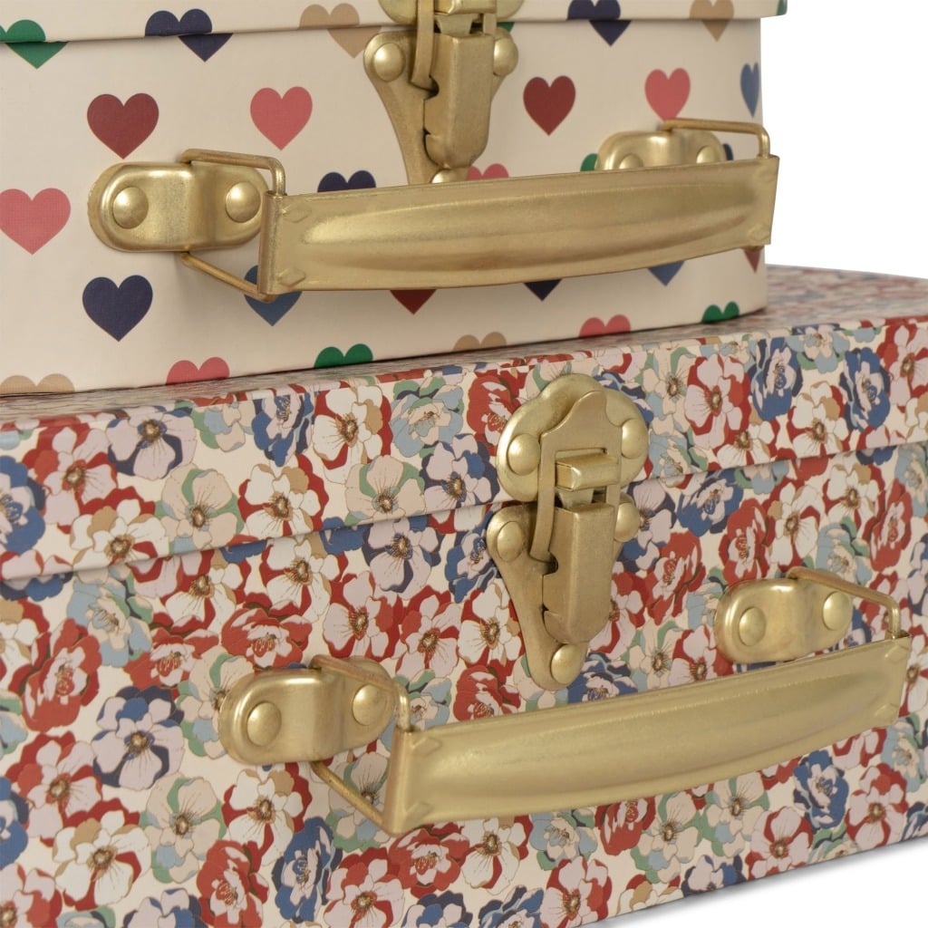 une petite valisette cœurs et une grande valisette fleurs Konges Slojd, zoom sur les motifs et les attaches sur fond blanc