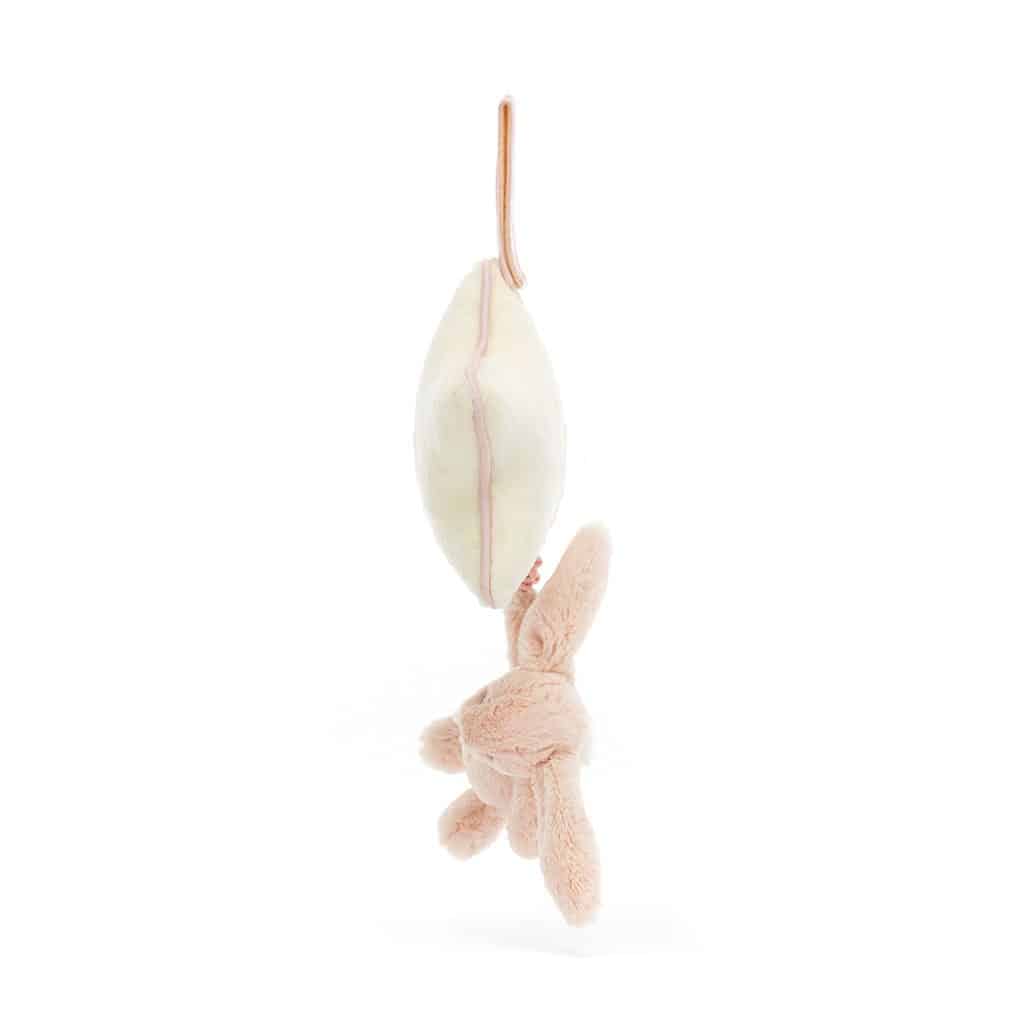 un doudou lapin rose musical Jellycat, vue de côté sur fond blanc