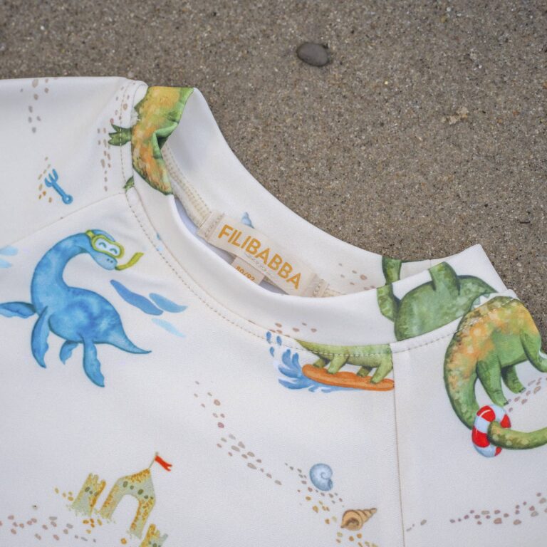 T-shirt anti UV dino beach Filibabba vue de près du col sur fond de sable