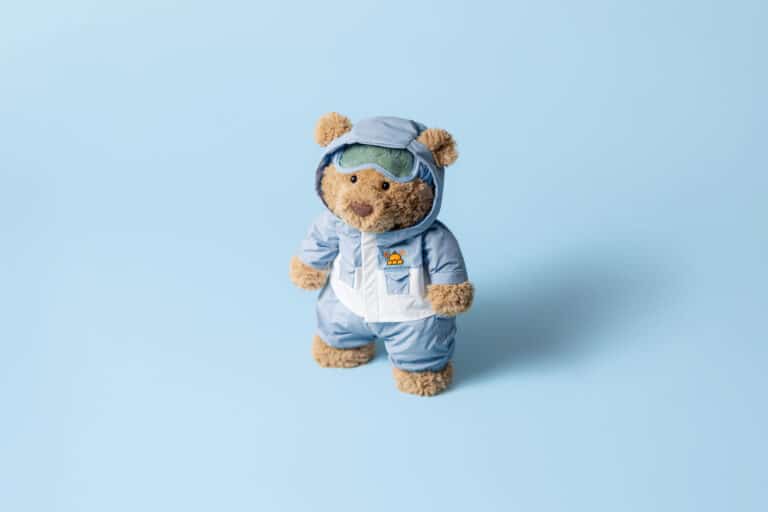 Doudou Ours Bartholomew en combinaison de neige bleue – Jellycat - Vu du dessus sur fond bleu