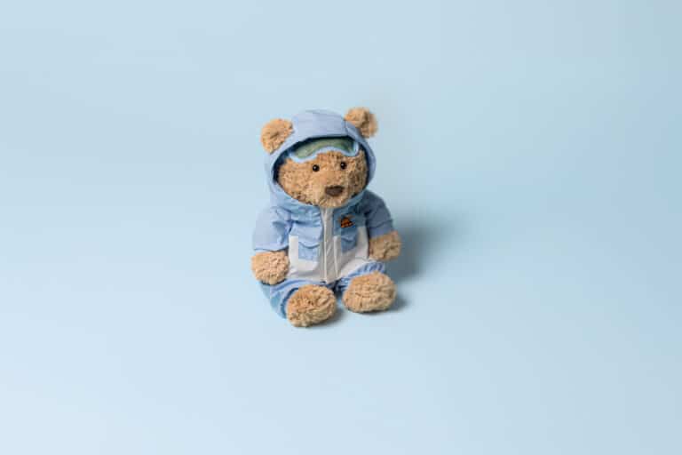 Doudou Ours Bartholomew en combinaison de neige bleue – Jellycat - Vu de face sur fond bleu