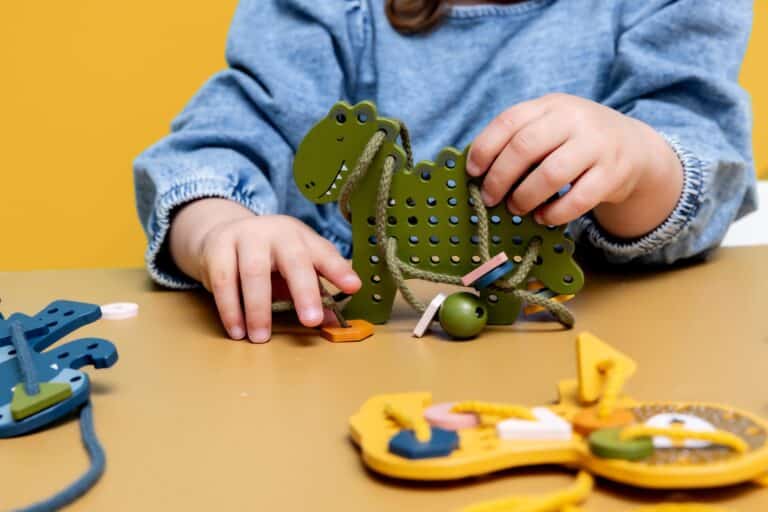 Jeux de laçage animaux en bois - Trixie Baby - Vue d'ambiance d'un enfant qui joue avec Mr Dino