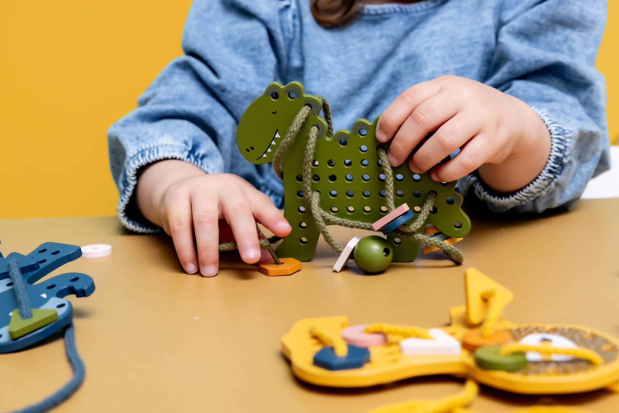 Jeux de laçage animaux en bois - Trixie Baby - Vue d'ambiance d'un enfant qui joue avec Mr Dino
