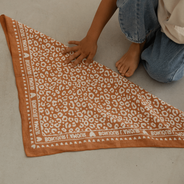 Petit foulard marron avec motif léopard crème - Atelier Wagram, vue déplié sur un fond d'ambiance
