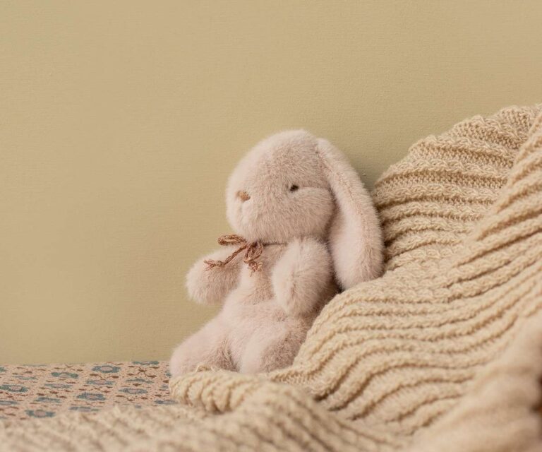 Mini doudou lapin rose clair - Maileg, vue de côté sur fond d'ambiance