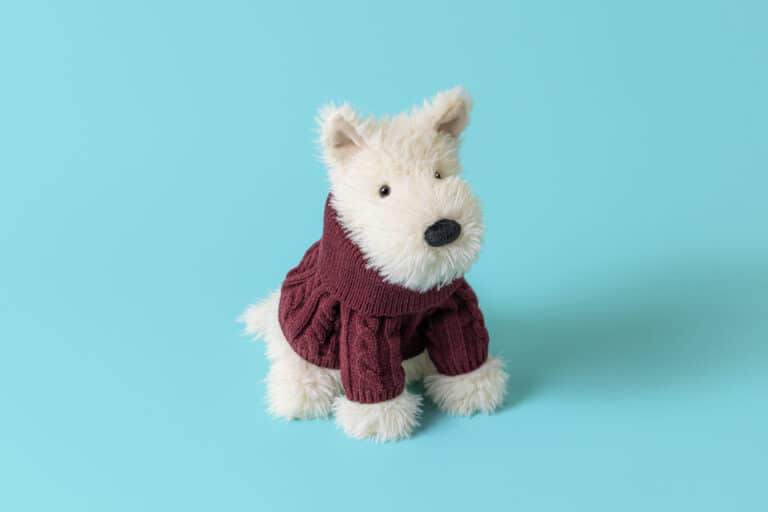 Munro Scottie Dog 'Winter Jumper' - Jellycat, vue de biais sur fond coloré